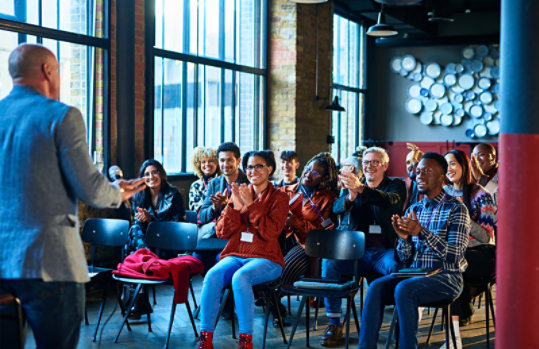 Coworkers meeting in an auditorium with a speaker in the front