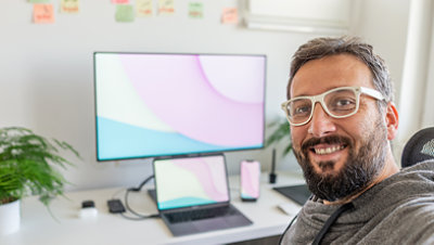 Man sits at a desk with a computer behind him