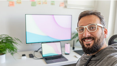 Man sits at a desk with a computer behind him