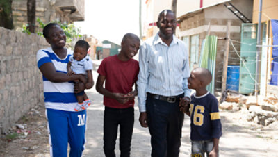 Smiling family walking together outdoors in a residential area, with two adults and three children enjoying a moment together.