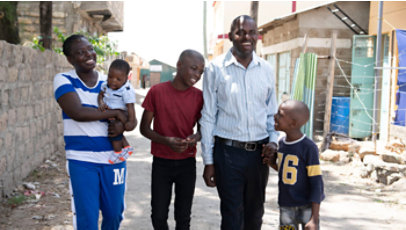Smiling family walking together outdoors in a residential area, with two adults and three children enjoying a moment together.