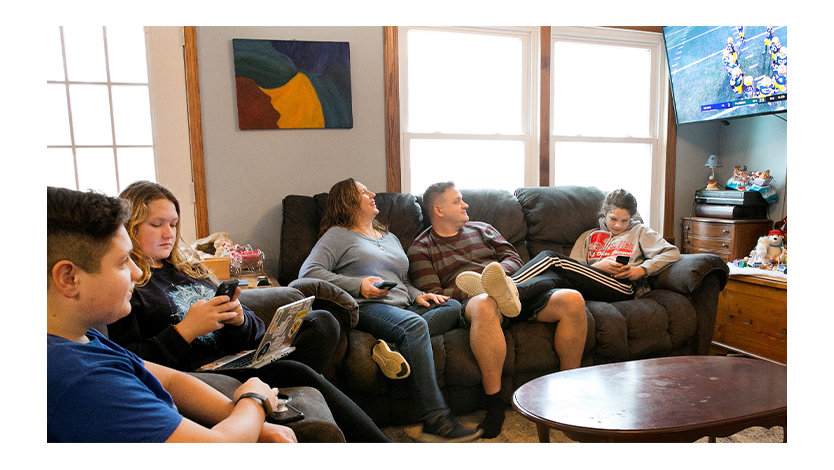 Family in a home sitting on couches and watching a football game