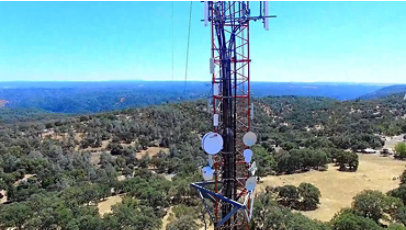 Tower in a rural area of California, rolling hills of evergreen trees extend far into the horizon.