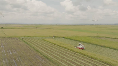 Aerial view of farming equipment progressing down a row of crops.