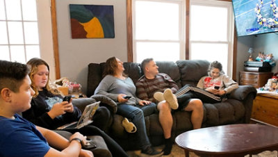Family in a home sitting on couches and watching a football game.