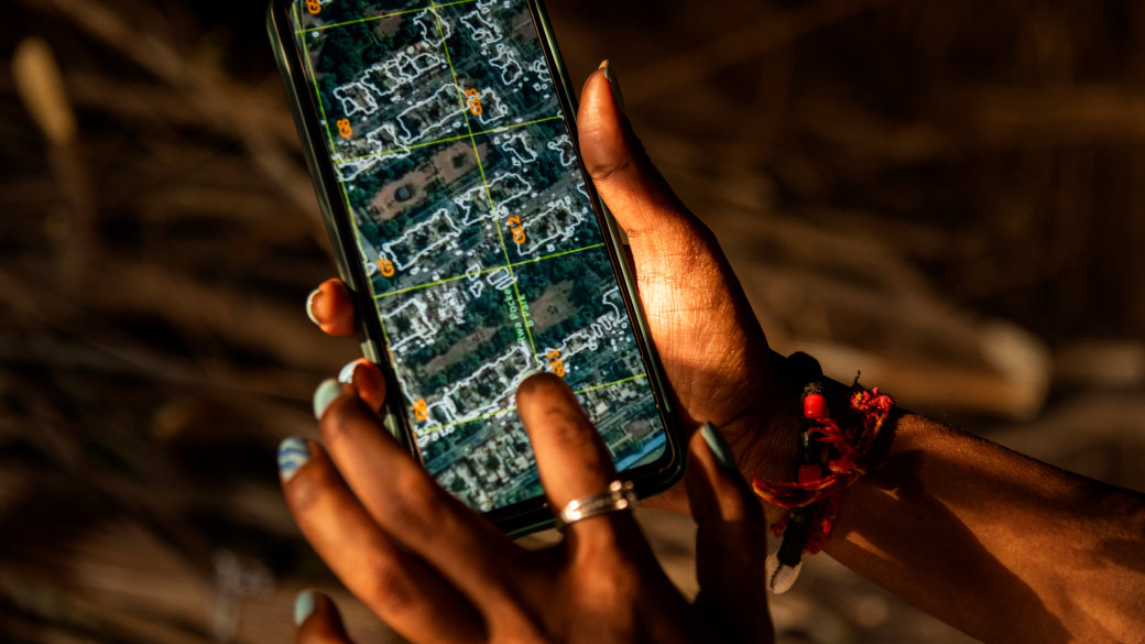 Close-up of a hand holding a phone displaying a map of satellite imagery.