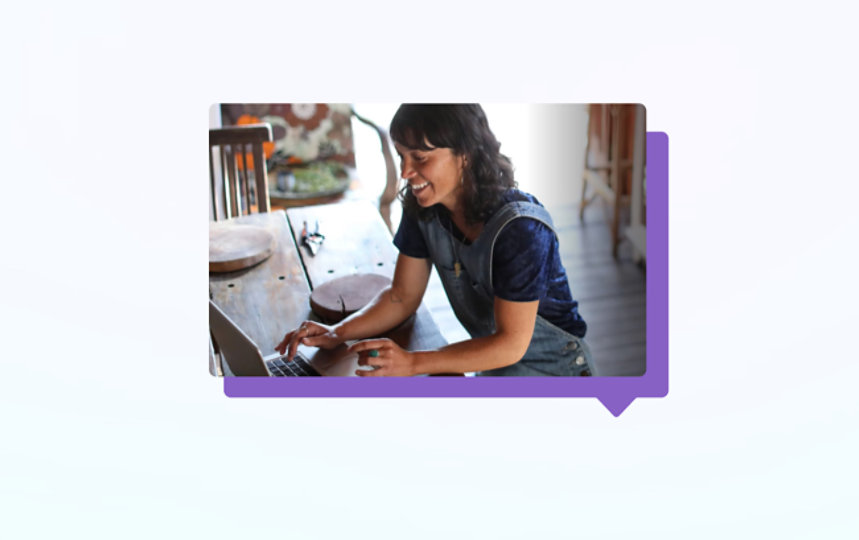 A casually-dressed woman works on a laptop at home.