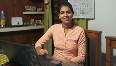 Manjusha M., a cybersecurity associate with CyberShikshaa, sits at a desk in an office in front of a laptop.