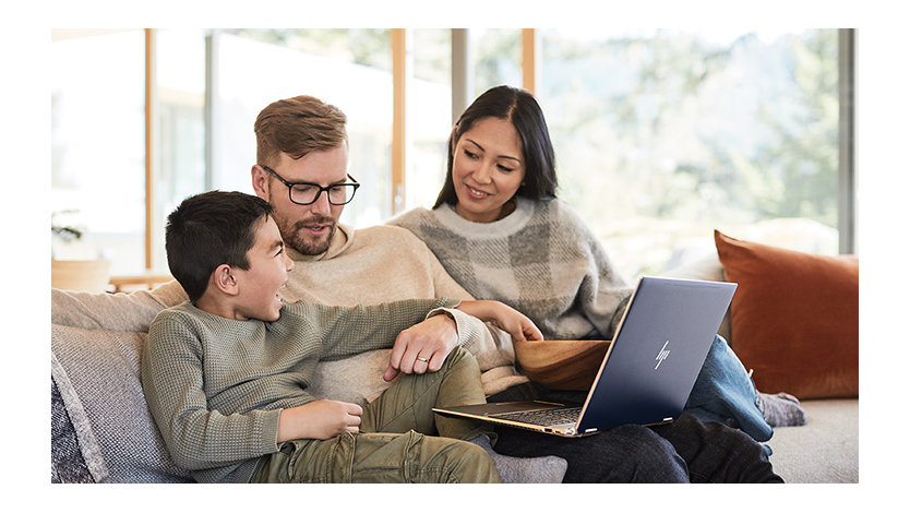 A family sitting on a couch and looking at a laptop together.