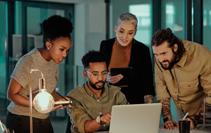 Group of workers gathered around a laptop computer.