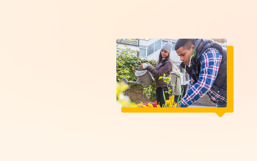 Two volunteers tend to a flower bed outside a corporate office.