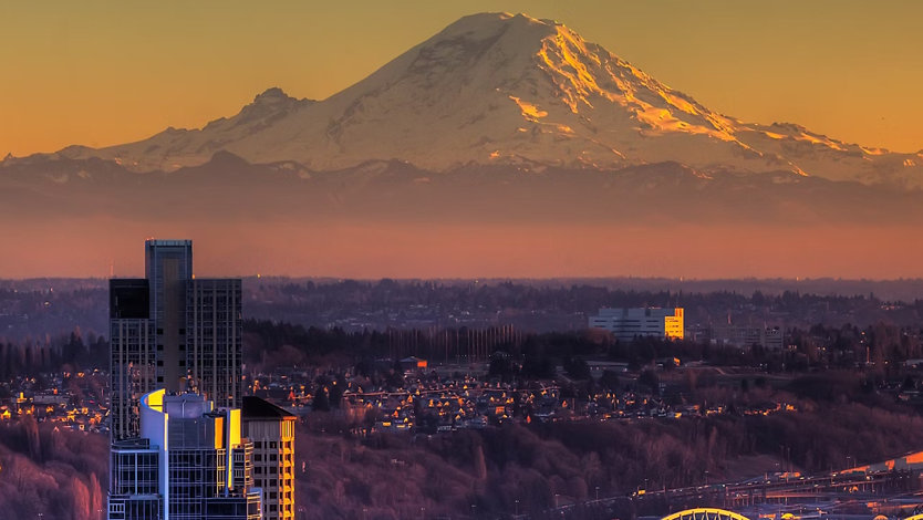 A panoramic view of the Seattle Waterfront at sunset against the backdrop of Mount Rainier.