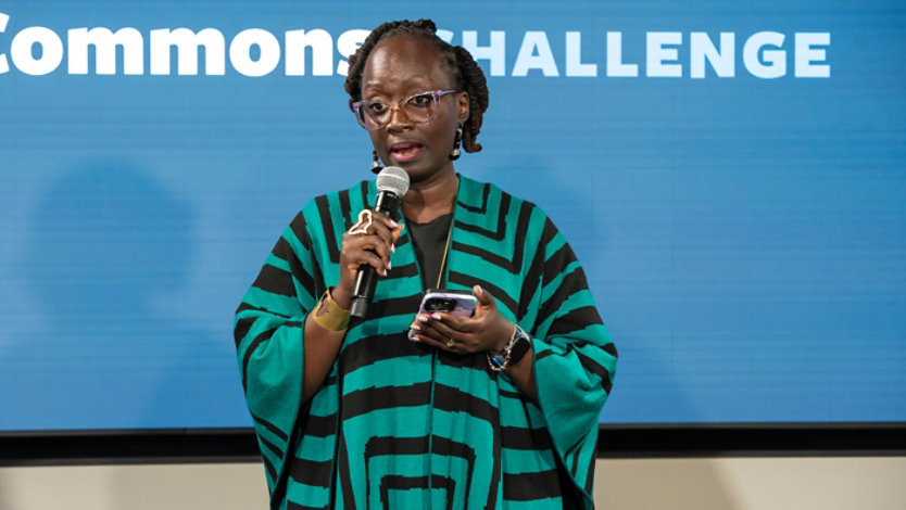 Woman speaking into a microphone on stage during a presentation.