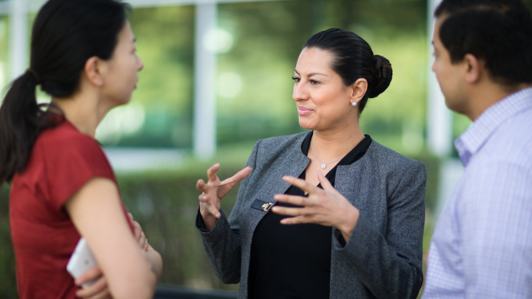 Three people having a discussion outside of an office building.