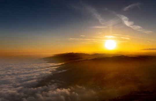 Golden sunrise over misty mountains and a sea of clouds.