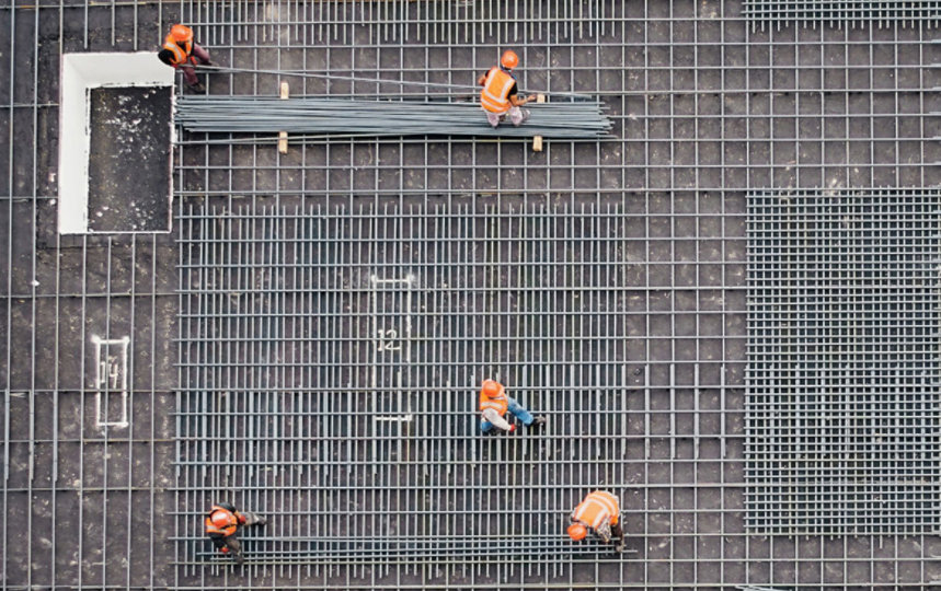 Aerial view of construction workers working on a steel grid foundation.