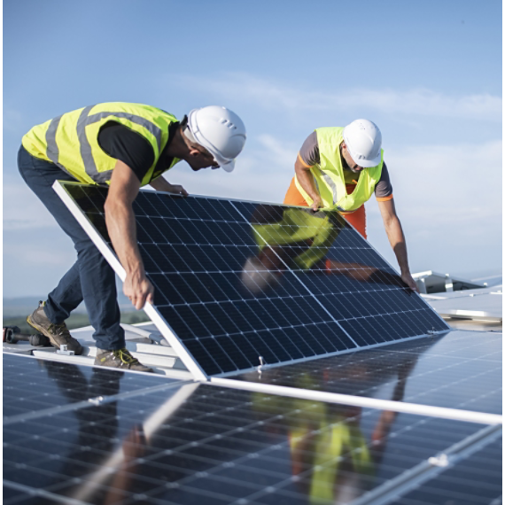 Two workers install solar panels on a rooftop under a clear sky.