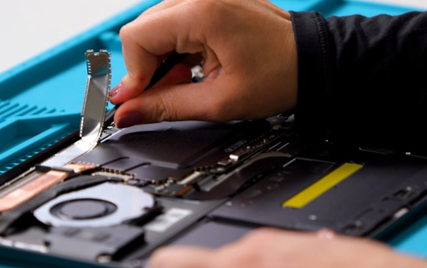 A person removes an old part from a Surface laptop.