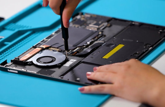 A person repairs a disassembled Surface device.