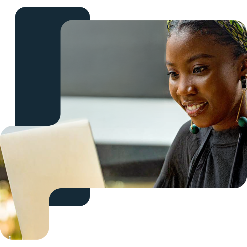 A woman smiling while using a laptop.