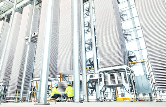 Two workers in safety gear working amidst the Heirloom direct carbon capture tower.