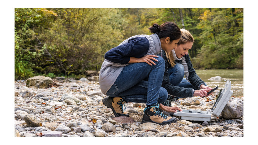 Natural river water samples are collected and tested by two women while a forest serves as the background.
