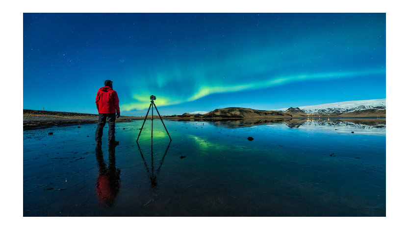 Silhouette of a man filming the northern lights.
