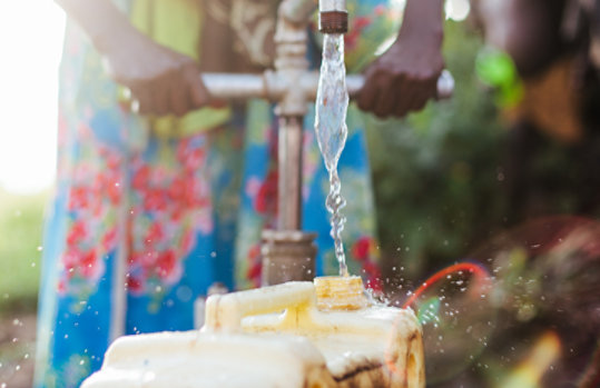Close-up of person running water from an outdoor tap in Africa.