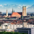 City skyline with twin-domed cathedral and distant mountains.