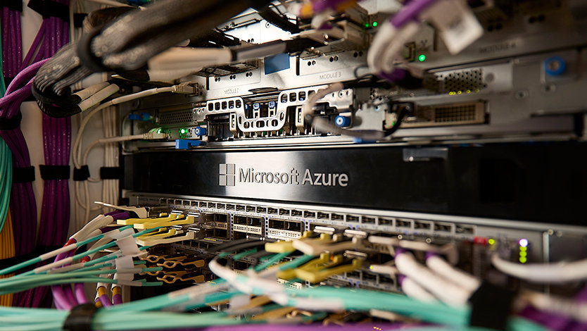 Datacenter close up of cold aisle rack with a metal face plate stamped with Microsoft Azure.