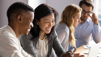 Happy mature businesswoman discussing a project on laptop with a young colleague.