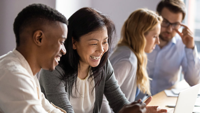 Happy mature businesswoman discussing a project on laptop with a young colleague.