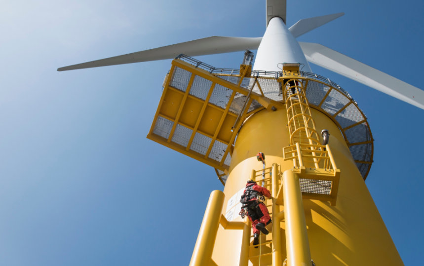 An engineer climbing a wind turbine to inspect it.