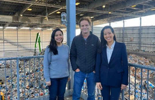 Microsoft Chief Sustainability Officer, Melanie Nakagawa standing with two Microsoft partners on a raised platform overlooking a waste sorting facility.