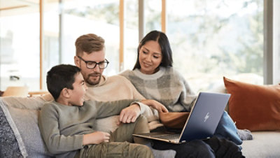 A family sitting on a couch and looking at a laptop together.