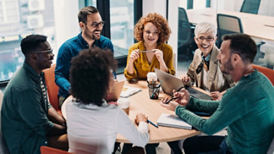 Group of business people having a meeting at a round conference table in a creative office.