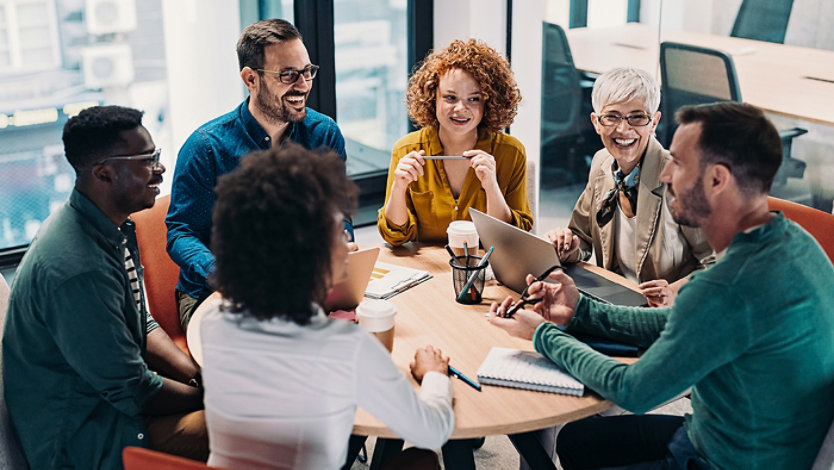 Group of business people having a meeting at a round conference table in a creative office.