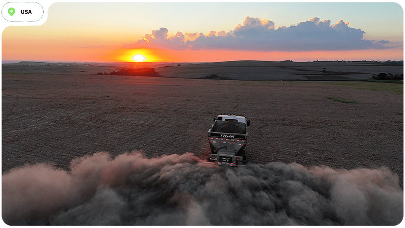 Vehicle driving on a dusty field at sunset in the USA.