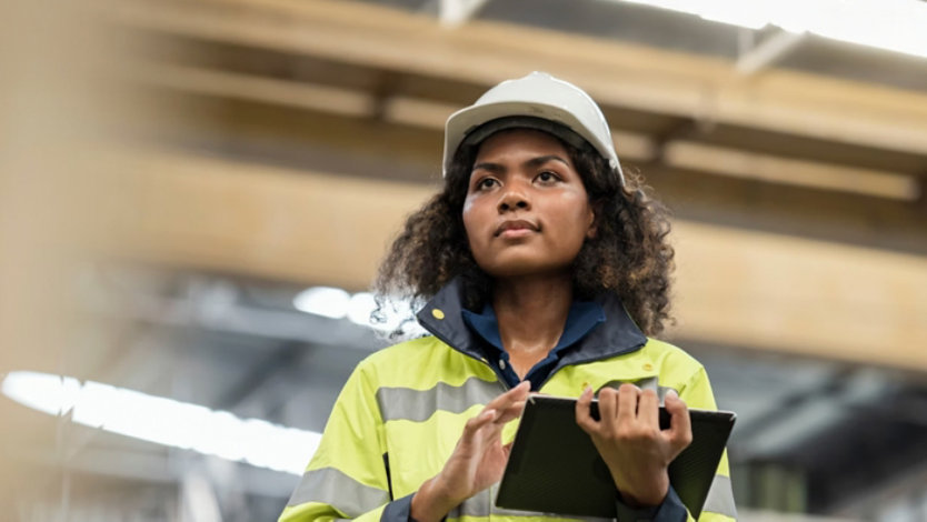 Woman wearing protective workwear using a tablet.