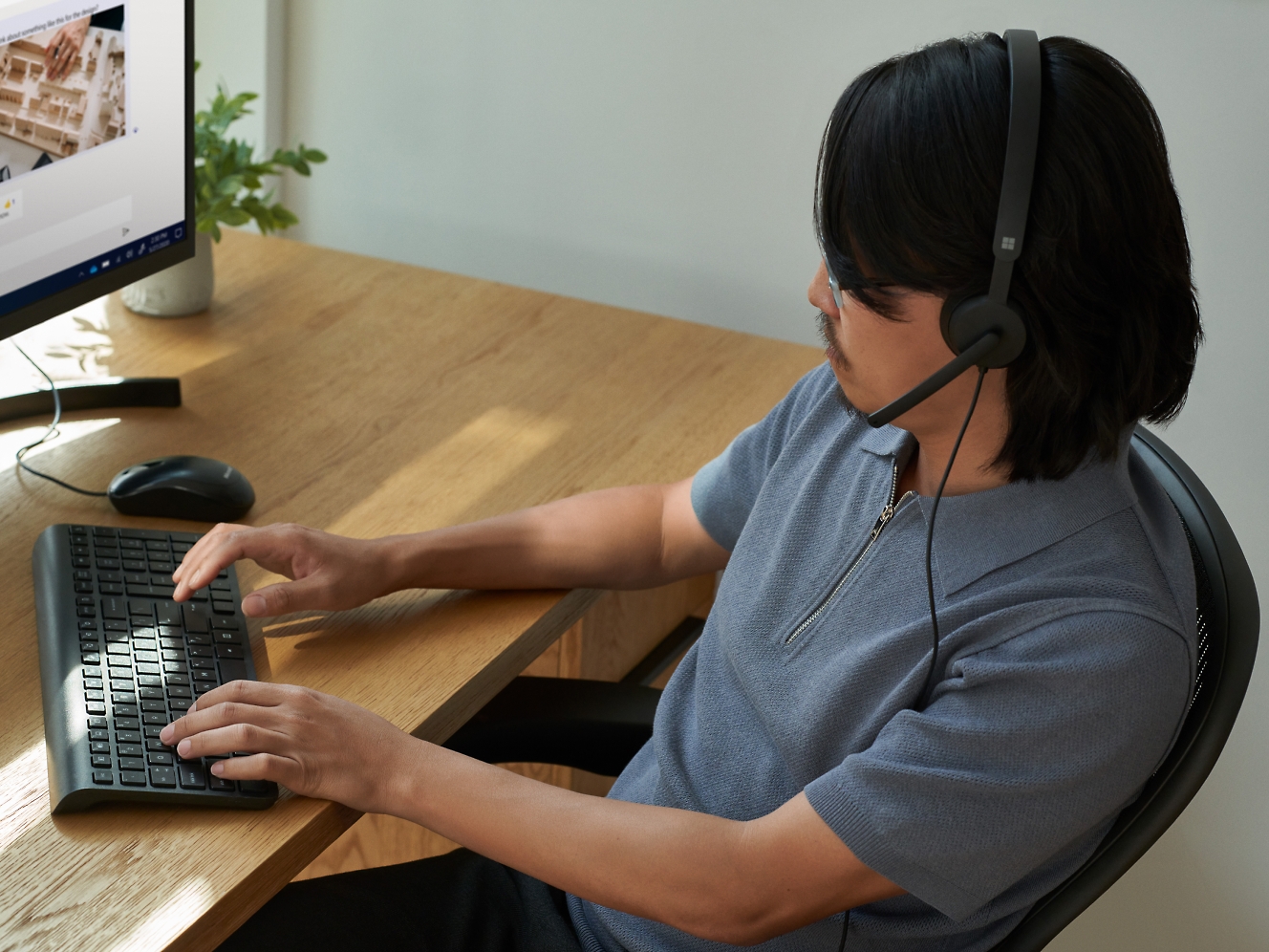 Mężczyzna korzystający z zestawu słuchawkowego podczas pracy na komputerze.