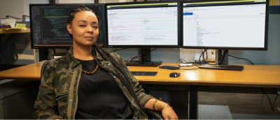 A woman sitting in front of two monitors