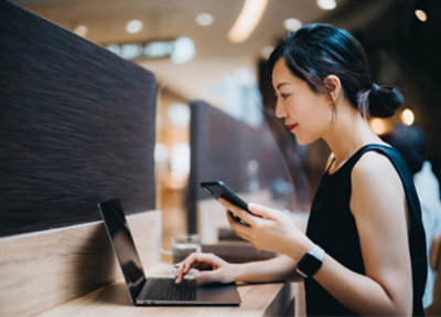 Eine Frau, die mit einem Laptop und einem Smartphone beschäftigt ist