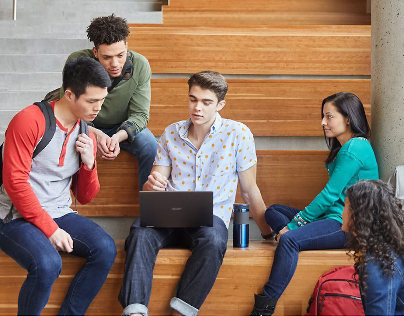 Un groupe d’étudiants assis sur un banc en bois avec un ordinateur portable.