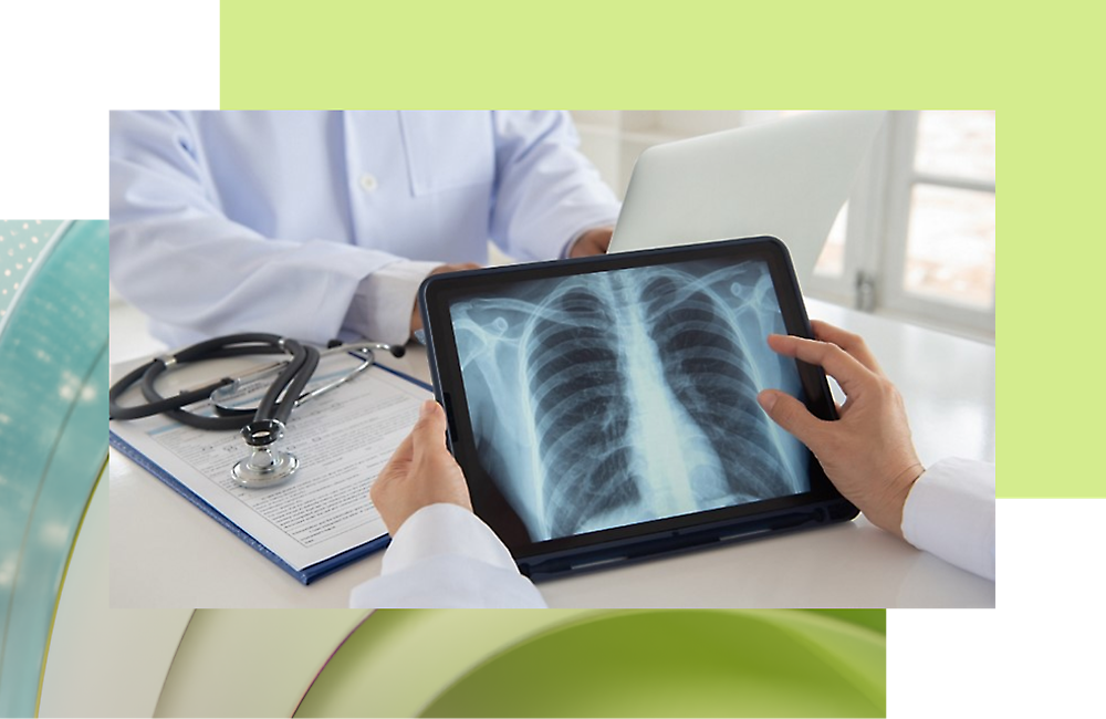 Ein Arzt schaut auf ein Tablet, das ein Röntgenbild anzeigt, während eine andere Person gegenüber sitzt und an ihrem Laptop arbeitet.