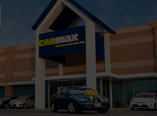 A CarMax storefront with cars parked in front
