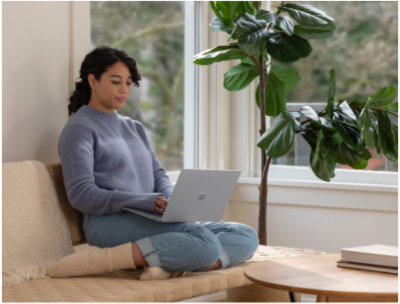 O persoană care se odihnește pe o canapea și utilizează un laptop.