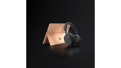A 13-inch, Dune Surface Pro with a pair of black Sony wireless headphones.