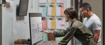 A person is showing a data chart on a computer to another person