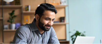 一個留著鬍子的人看著膝上型電腦。