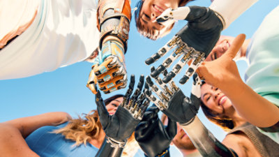 Six young adults hold their hands together, showing they all have different types of prosthetic arms.